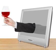 red wine glass in male hand leans out TV screen photo