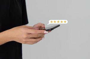 mano de mujer usando un teléfono inteligente móvil con icono de cinco estrellas servicio al cliente experiencia retroalimentación revisión satisfacción. foto