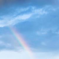 rainbow in rain clouds in blue evening sky photo