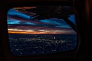 el crepúsculo de la noche desde el avión a reacción ve el cielo azul naranja rojo con la luz de la ciudad de Tailandia debajo foto