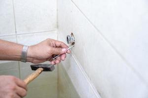 Asian man tries to fix and repair pipe shower in the old restroom. photo