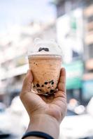 bubble ball ice Milk Tea in the hand with blur Asia building background. photo