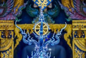 Gold rowel, the symbol of buddhist religion on the Thai blue art style pole with temple background. photo