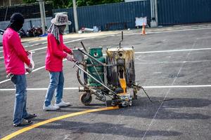 los trabajadores están recubriendo el asfalto con pintura termoplástica por máquina foto