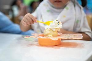 kid is eating ice-cream and whip cream in the icecream restaurant photo