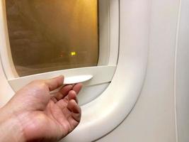 close up hand holding the cover plane window to close and open photo
