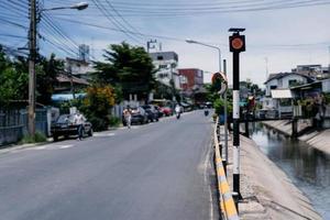 traffic light pole with only red light on it between canal and road in the local road at Thailand photo