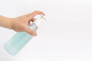 Asian mand hand holds a gel alcohol pump bottle and ready to pushes on it. It's an isolated object on the white clear screen in studio light. photo