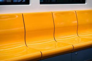 Close up to the yellow chairs that are set on the row inside the train photo