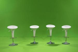 White 4 studio Chairs are settled in front of a green screen in studio light around. photo