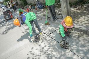 workers drop asphalt liquid into the hole of street. photo