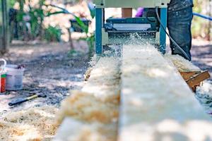 worker scrubs the big long wood plate with polishing machine in the garden. photo