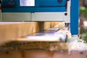 worker scrubs the big long wood plate with polishing machine in the garden. photo