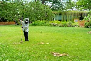 Gardener sweeps dried bamboo leaf on the grass field in the garden. photo