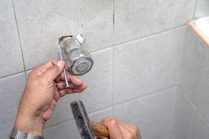 Asian man tries to fix and repair pipe shower in the old restroom. photo