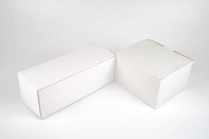 dos cajas blancas de papel, altas y gordas, yacen sobre el fondo blanco en una foto de estudio con una hoja de recorte.