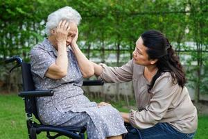 Caregiver help Asian elderly woman disability patient sitting on wheelchair in park, medical concept. photo