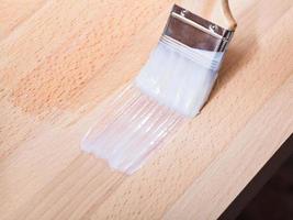 putting varnish on surface of beech top table photo