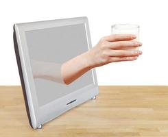 hand holding glass of milk leans out TV screen photo