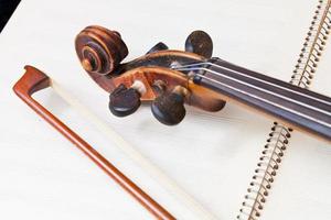arco de violín y pergamino en el libro de música foto