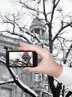 turista tomando fotos de nieve en un árbol desnudo