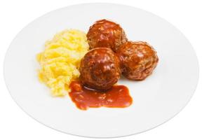 portion of roasted meatballs under meat sauce and mashed potato on plate isolated on white background photo