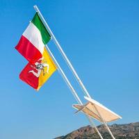 Italian and Sicilian flags and blue sky photo