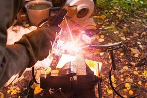 Welder welds iron ring outdoors photo