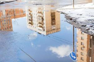 urban houses and sky reflected in puddle in spring photo