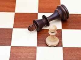 standing and fallen chess king and pawn photo