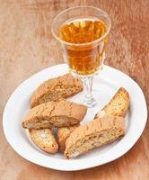 copa de vino y cantuccini italiano de almendras en la mesa foto