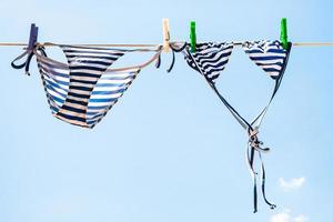 Striped female swim suit is dried on clothesline photo