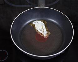 small piece dairy butter melting on pan photo
