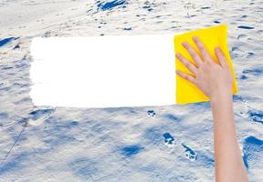 hand deletes snow surface by yellow rag photo