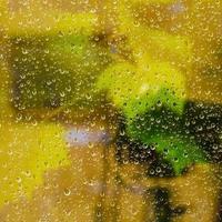 yellow background from raindrops on window pane photo