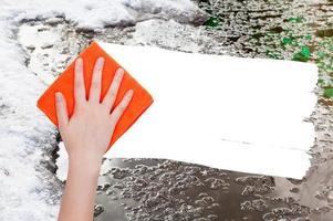 hand deletes melting snow by orange rag photo