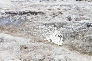 charco de nieve derretida en la ciudad foto