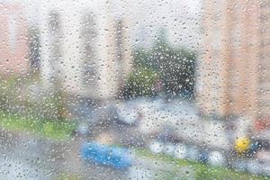 view of raindrops on windowpane of urban house photo
