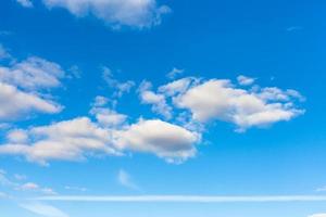 blue sky with clouds and horizontal airplane trail photo