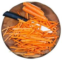 wooden cutting board with raw strips sliced carrot photo