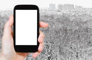 teléfono inteligente y bosque nevado cerca de la ciudad foto