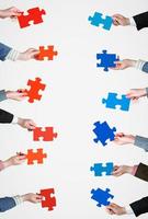 red and blue puzzle pieces in people hands photo