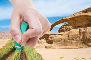 hand deletes sand in desert by rubber eraser photo