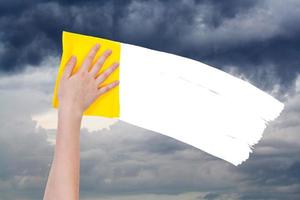 la mano elimina el cielo nublado por un trapo amarillo foto