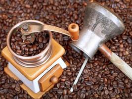 coffee grinder and copper pot on roasted beans photo