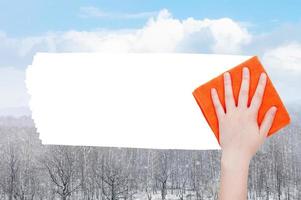 hand deletes snow over forest by orange rag photo