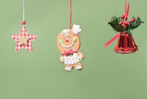 hanging christmas ornamental decoretions, star, red bell and gingerbread Man. Merry christmas card on green background. winter holiday minimal set. photo