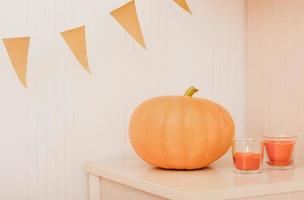 pumpkin and orange flags bunting. glowing candles with pumpkin fragrance. home decor for halloween celebration. autumn harvesting, seasonal decor. photo