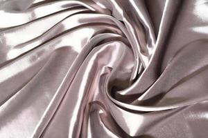 Silk Fabric Background, beige Satin Cloth Waves, Abstract Waving Textile with shining texture. woman apparel sewing concept. photo