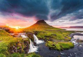 paisaje de puesta de sol sobre la montaña kirkjufell con cascada kirkjufellsfoss y colorida nube pileus en verano en islandia foto